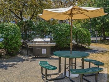 A table and chairs with an umbrella and a grill